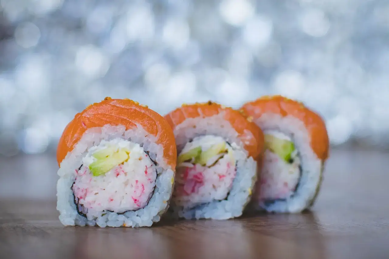 Trzy rolki sushi z łososiem i awokado, idealne na japońską ucztę.