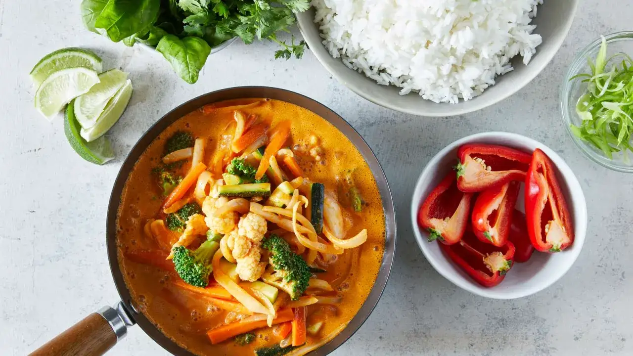 Aksamitny kurczak w czerwonym curry z warzywami, podany z ryżem, limonką i papryczką.