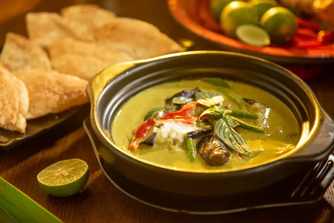 Aksamitne curry po tajsku z kawałkami bakłażana, fasolki szparagowej i papryki, podane z chrupiącym pieczywem i limonką.
