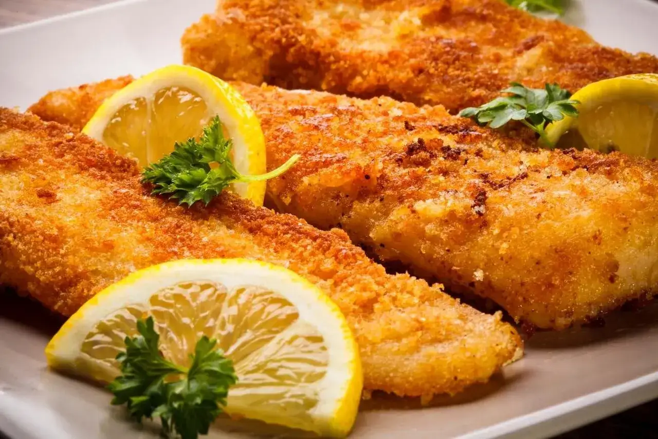 Chrupiące filety rybne, idealnie jak panierować w panko, podane z plasterkami cytryny i natką pietruszki.