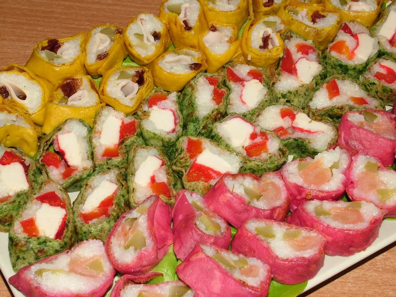 Kolorowe rolki sushi w naleśniku, z łososiem, paluszkami krabowymi i warzywami. Pyszne sushi w naleśniku nazwa.