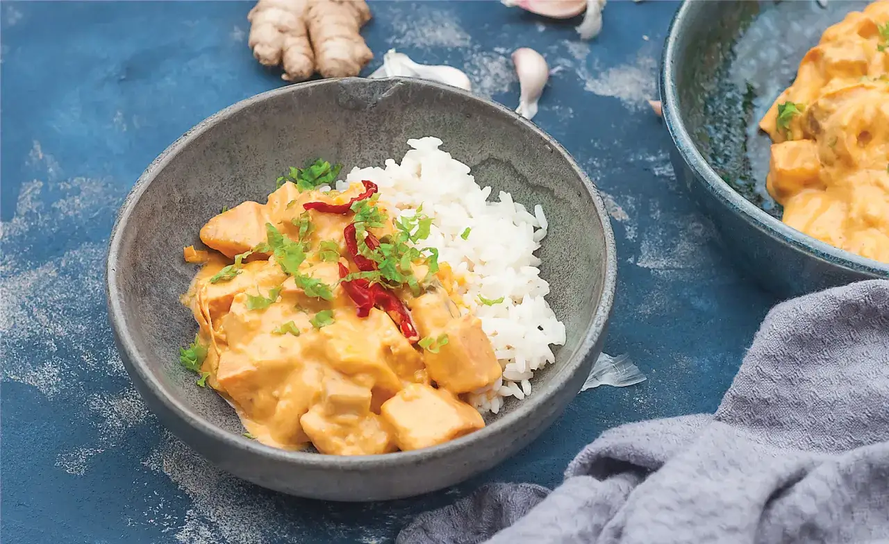 Aksamitne tajskie curry z tofu, podane z ryżem, ozdobione chili i szczypiorkiem.