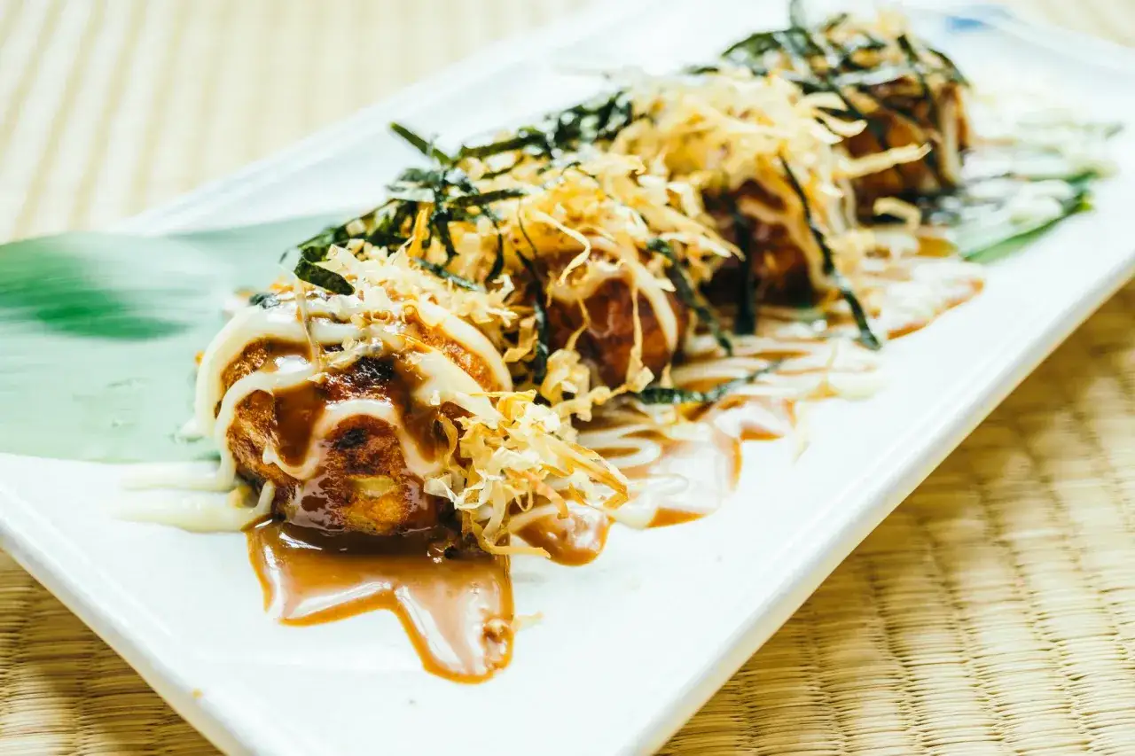Pyszne takoyaki, idealne do domowego przepisu, polane sosem i majonezem, posypane wiórkami bonito i nori.
