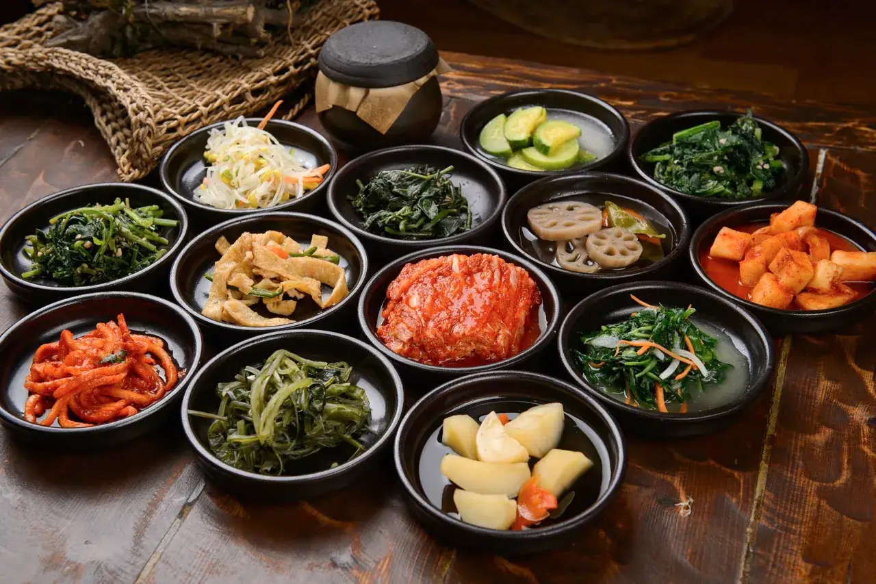 Bogactwo koreańskich przystawek: kimchi, marynowane warzywa, sałatki z ziół i kiełków fasoli.