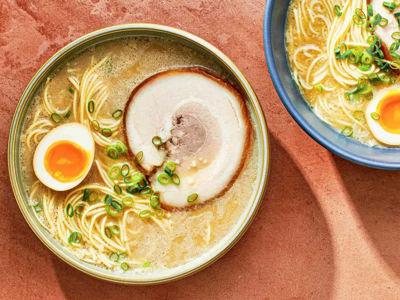 Dwa talerze aromatycznego ramenu z makaronem, jajkiem na pół, plastrem wieprzowiny i szczypiorkiem. Pyszne danie, które kusi, jak smakuje ramen.
