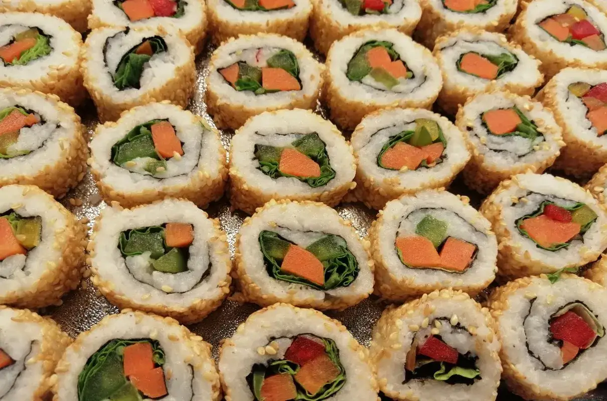 Roladki sushi z sezamem, w środku zielona sałata, marchewka i og&oacute;rek. Idealne warzywa do sushi na lekki posiłek.