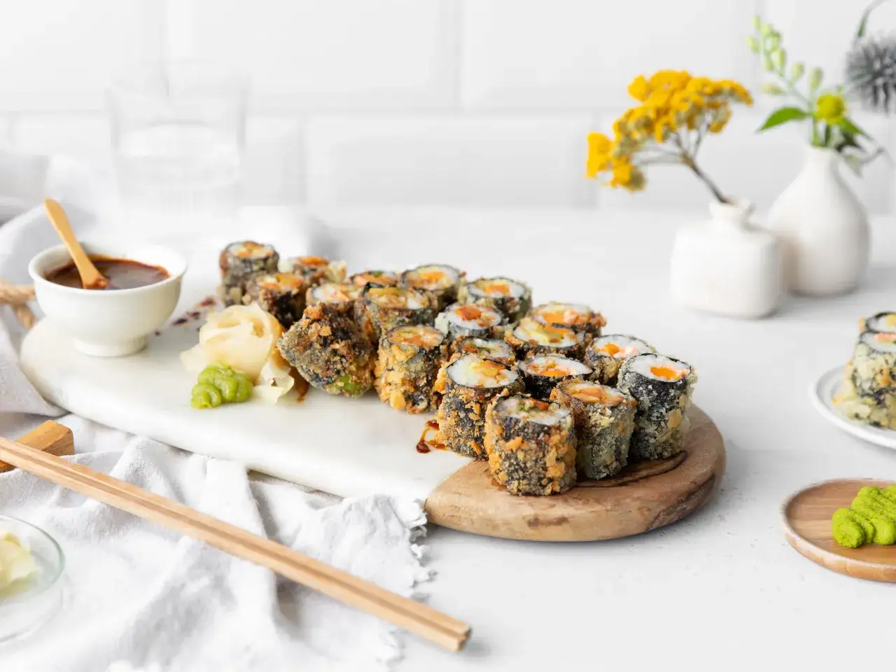 Chrupiące sushi w tempurze, podane z sosem i wasabi, kuszą apetycznym wyglądem.