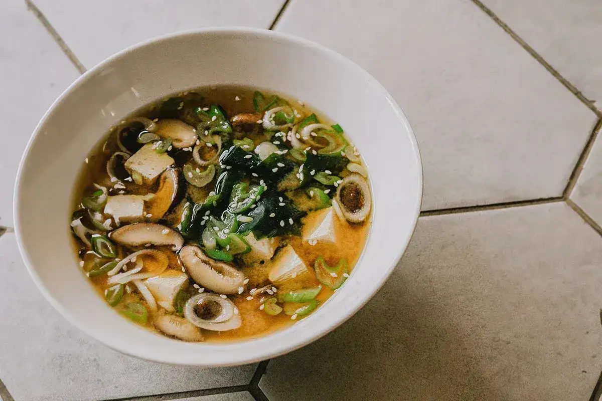 A miska pełna aromatycznej zupy miso z tofu, grzybami shiitake, wodorostami wakame i szczypiorkiem.