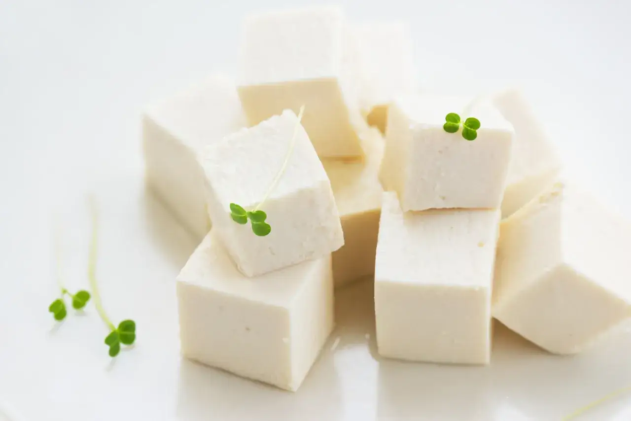 Świeże, białe kostki domowego tofu, ozdobione zielonymi kiełkami. Idealne do zdrowych posiłków.