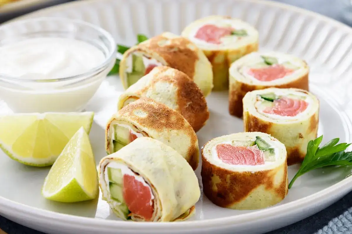 Sushi w naleśniku nazwa: rolki z łososiem, ogórkiem i serkiem, podane z dipem i limonką.