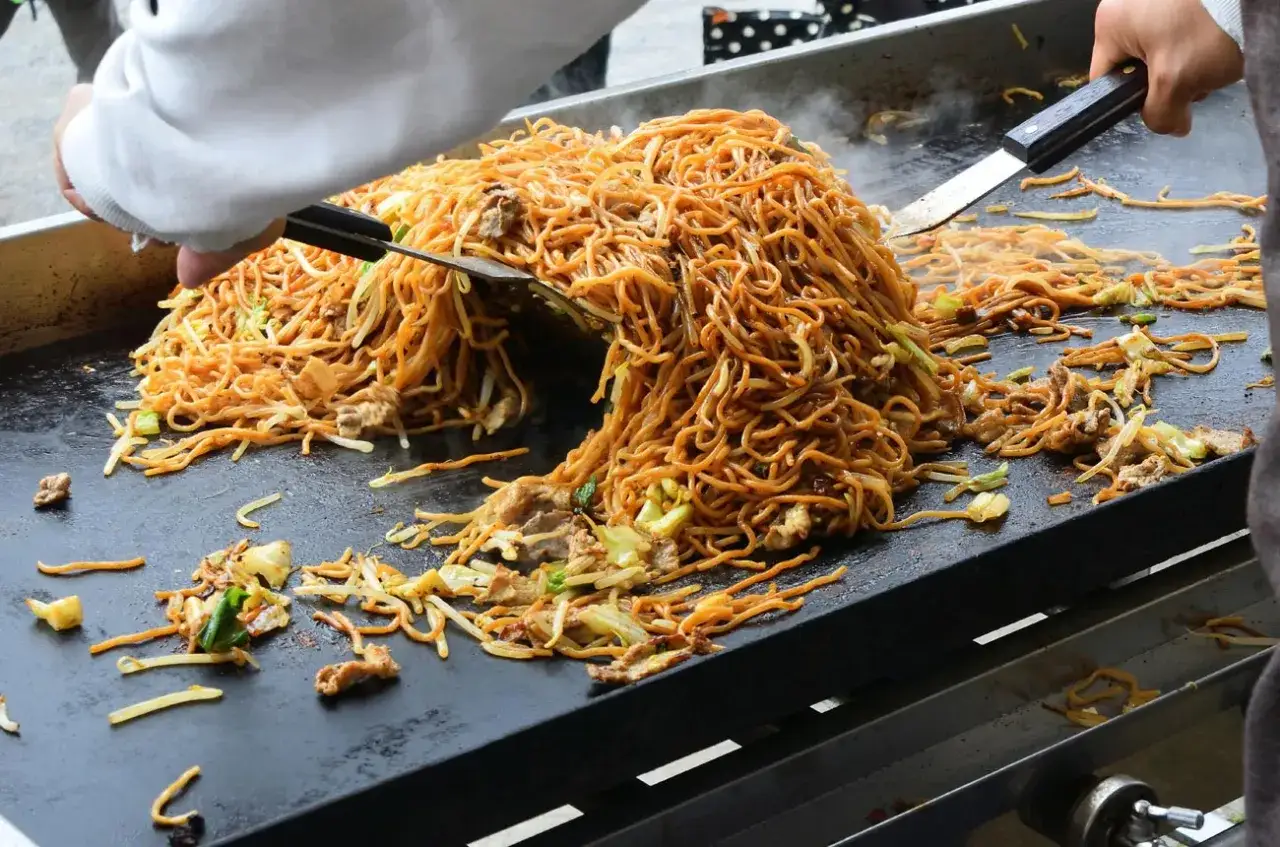 Smażone makaron yakisoba z warzywami i mięsem na płycie grillowej. Idealny przepis na szybki obiad.