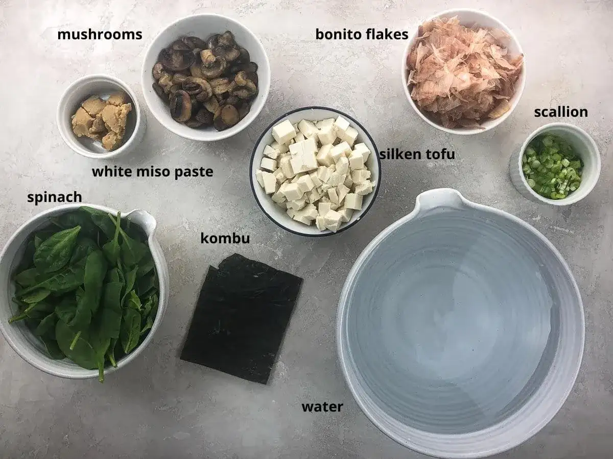 Składniki do zupy miso shiru: tofu, grzyby, szpinak, pasta miso, wodorosty kombu, płatki bonito, szczypiorek i woda.