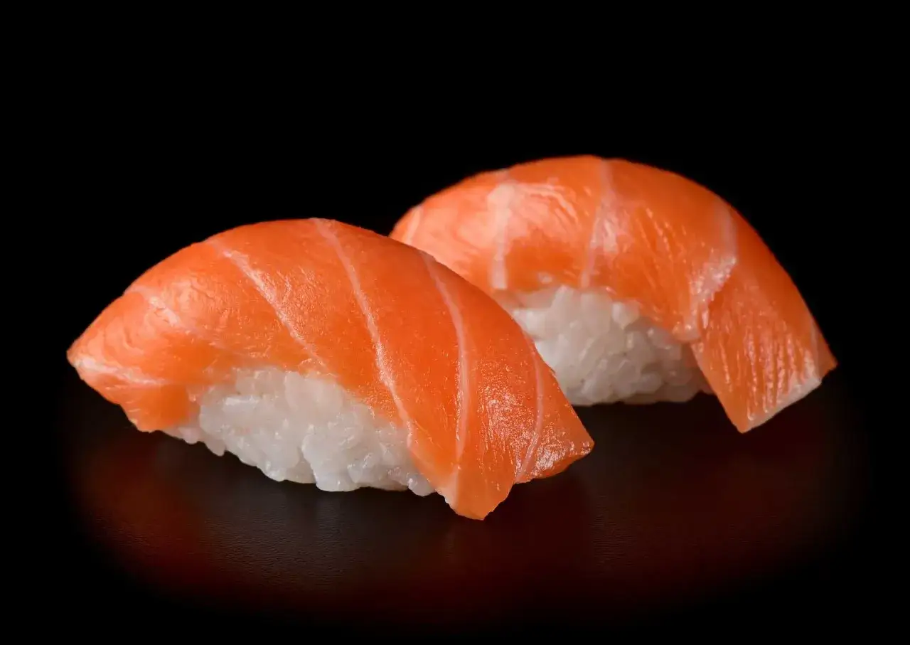 Dwa kawałki sushi z łososiem, idealna ryba do sushi, na czarnym tle.