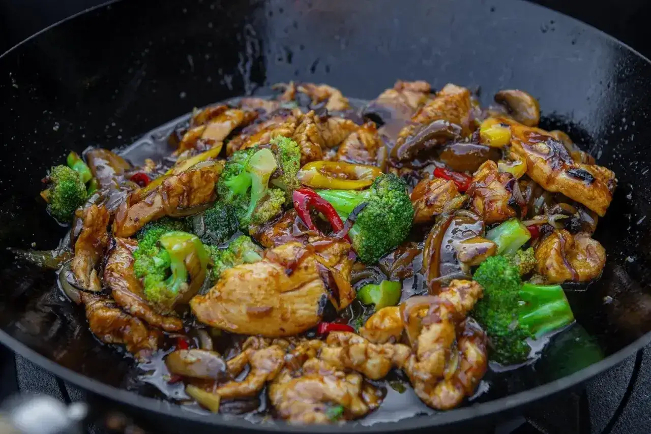 Pyszne kiełki stir fry z kurczakiem, brokułami i papryką w sosie, przygotowywane w woku.