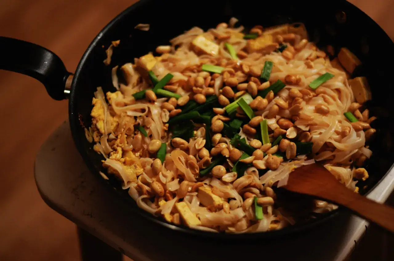 Makaron ryżowy z orzeszkami ziemnymi, szczypiorkiem i tofu, gotowy do polania sosem do pad thai.