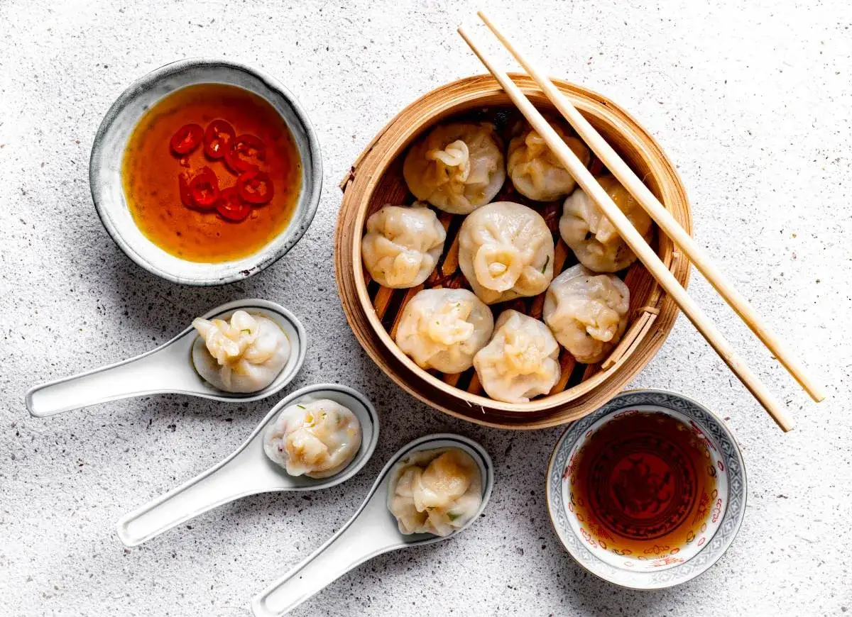 Pyszne dim sum w bambusowym parowniku, podane z sosami i chili. Idealna przekąska.