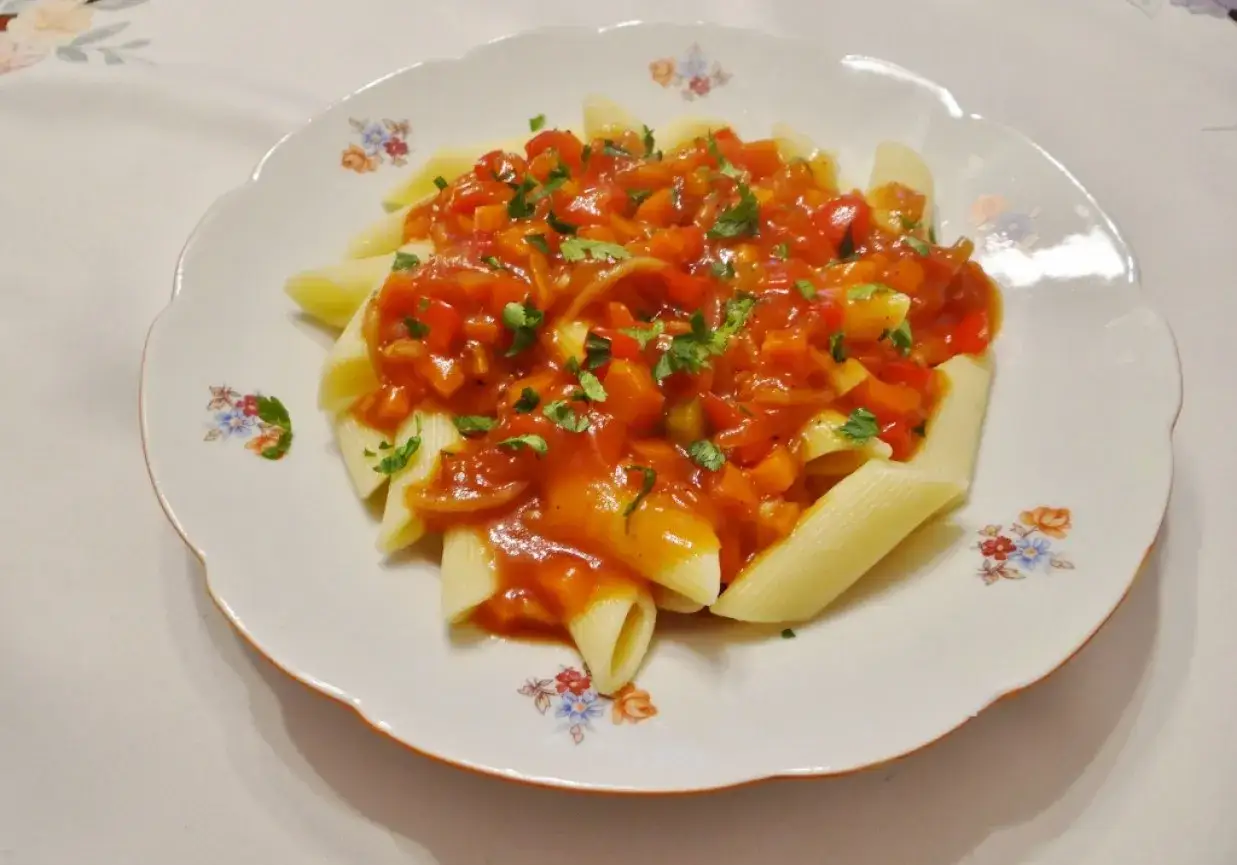 Penne z aromatycznym, słodko-kwaśnym sosem warzywnym, posypane świeżą natką pietruszki.